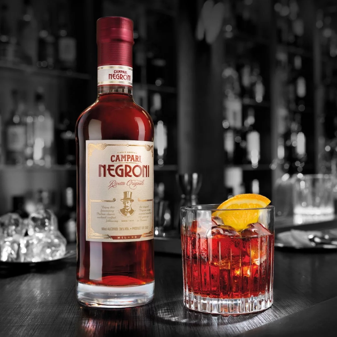 A bottle of Campari next to a Negroni cocktail